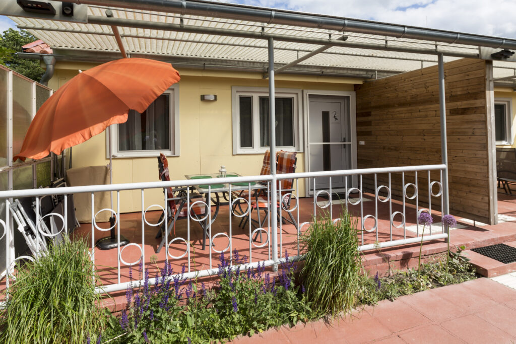 Ferienhausmit Terasse, Tisch, Stühlen und Sonnenschirm